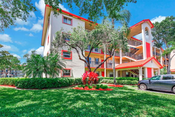 Front view of a multi-story residential building with balconies and a red roof.