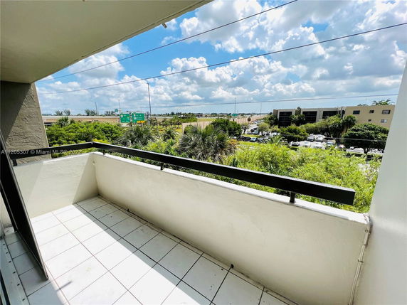 View from a balcony showing surrounding areas with buildings and greenery in the distance.