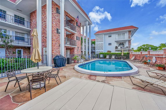 Outdoor area with a swimming pool and adjacent multi-story brick building.