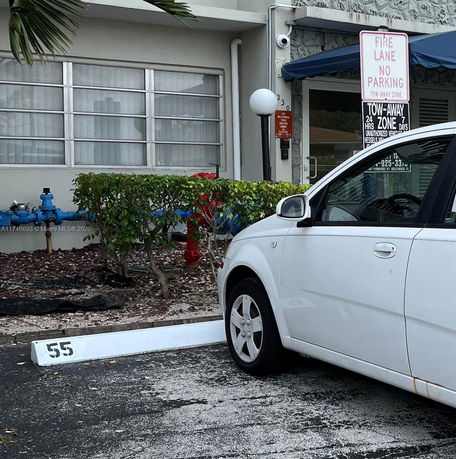 Outdoor parking space with a parked white car and building in the background.