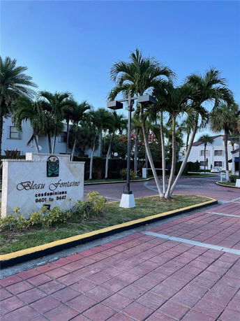 Front view of condominiums with palm trees and a sign reading 'Bleau Fontaine Condominiums'.