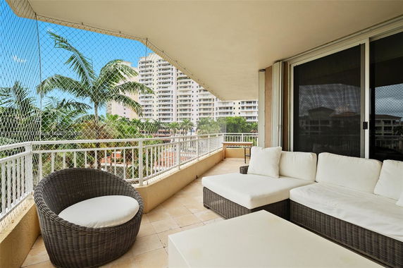 Balcony view with outdoor furniture overlooking surrounding buildings and palm trees.