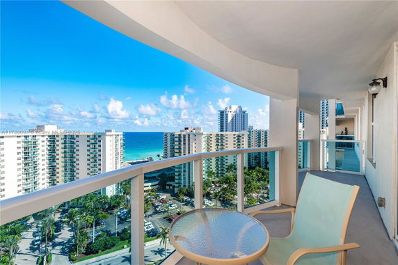 View from a high-rise building balcony overlooking other buildings and the ocean.
