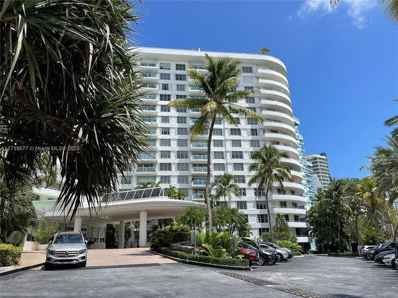 Front view of a multi-story residential building with curved balconies and a covered entrance.
