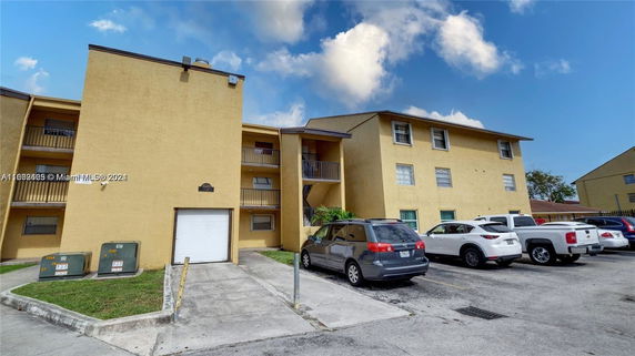 Front view of a multi-story residential building with a parking area.