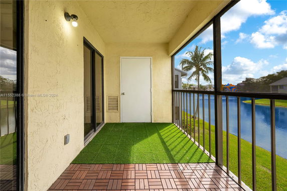 Screened balcony overlooking a waterway with palm trees and blue sky.