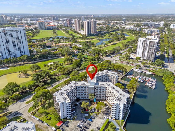 Aerial view of a large residential complex with multiple buildings surrounded by green areas and waterways.