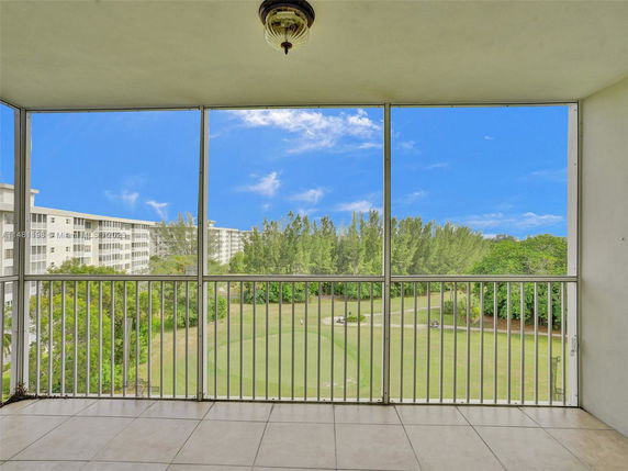 View from a balcony overlooking trees and a clear blue sky.