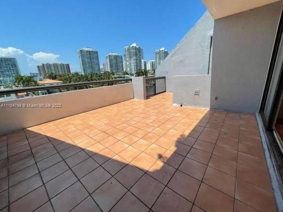 Rooftop area with tiled flooring and a view of high-rise buildings in the distance.