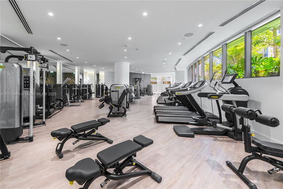 Interior view of a modern gym with various exercise equipment and large windows.