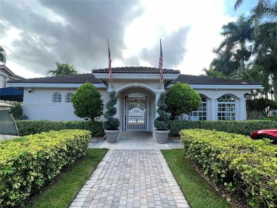 Front view of a single-story house with a gated entrance and two flags on the roof.