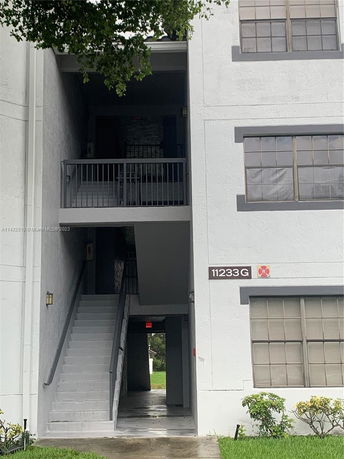 Front view of a multi-story building entrance with exterior stairs.