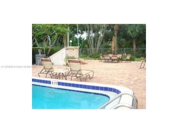 Outdoor swimming pool area with lounge chairs and tables.