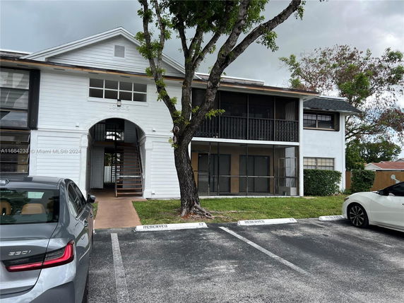 Front view of a two-story building with a central staircase and screened balconies.