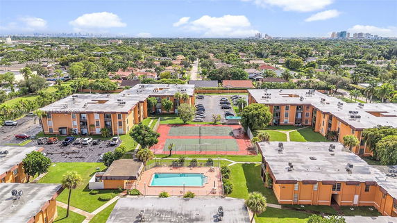 Panoramic view of a residential complex with multiple buildings, a swimming pool, and tennis courts.