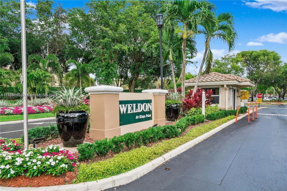 Entrance view with signage and guardhouse, surrounded by landscaping.