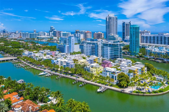 Aerial view of a cityscape with colorful buildings along a waterfront and high-rise structures in the background.