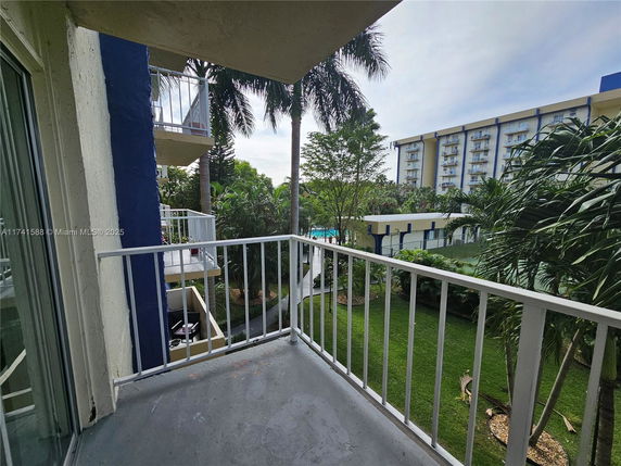 View from a balcony overlooking a garden and distant buildings.