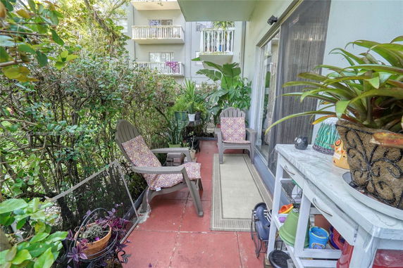 Outdoor patio area with chairs and plants, adjacent to a multi-story building.
