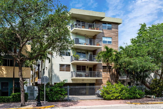Front view of a multi-story residential building with balconies and gated entrance.
