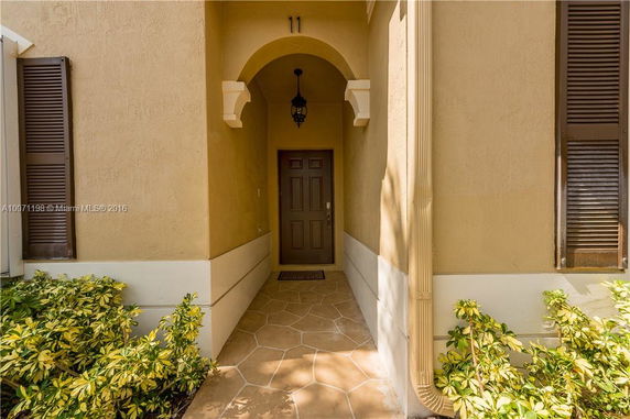Front entrance of a house with an archway and a brown door.