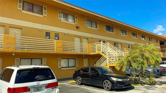 Front view of a multi-story building with a yellow facade and external staircases.