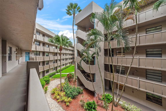 View of a multi-story apartment complex with balconies and a landscaped courtyard.