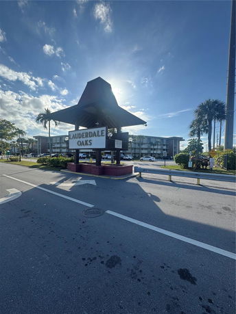 Front view of a multi-story residential building with a sign reading 'LAUDERDALE OAKS' at the entrance.