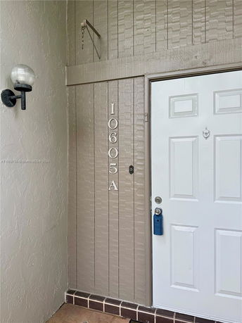 Front entrance of a building with a white door and wall light fixture.