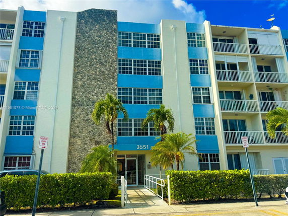 Front view of a multi-story residential building with a stone accent feature and balconies.