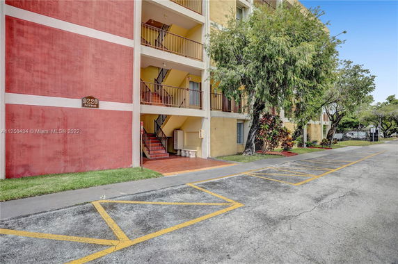 Front view of a multi-story apartment building with red and yellow exterior.