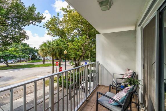 Balcony view overlooking a street with trees and stop signs.