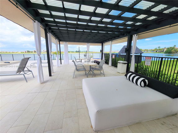 Rooftop lounge area with chairs and a shaded seating space overlooking water.