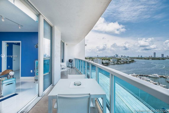 Balcony view from a high-rise building overlooking a cityscape and body of water.