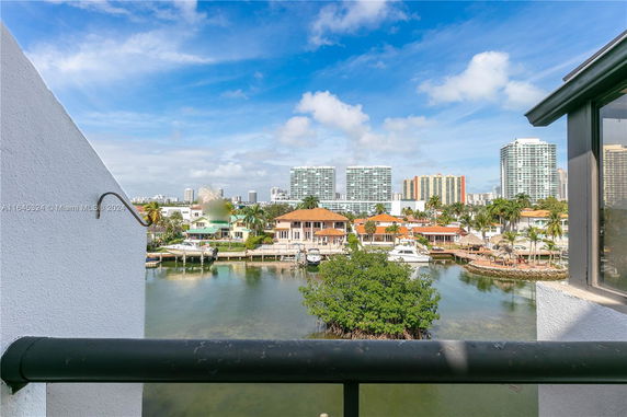 Panoramic view from a building showing several waterfront homes and high-rise buildings in the background.
