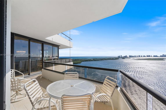 View from a high-rise balcony overlooking water and distant buildings.