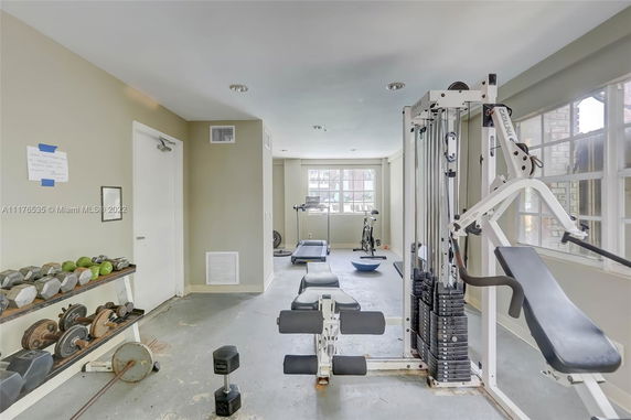 Indoor gym with exercise equipment, including dumbbells and a weight machine.