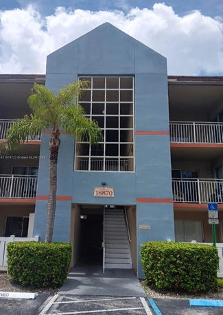 Front view of a multi-story building with a central entrance and balconies.