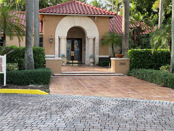 Front view of a house with a red tile roof and archway entrance.