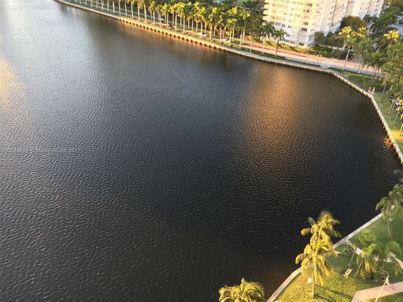 View of a body of water surrounded by palm trees and buildings, as seen from a high vantage point.