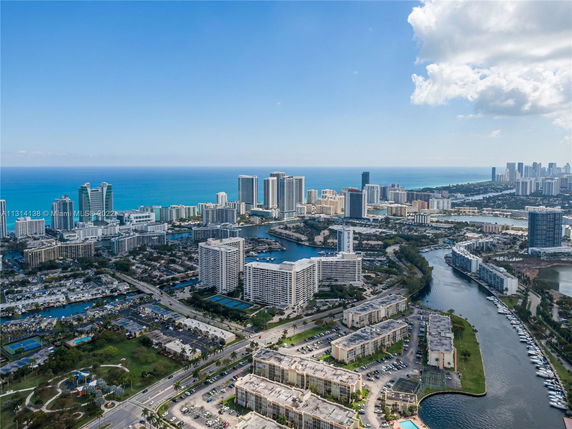 Panoramic view of a coastal city with numerous high-rise buildings, waterways, and the ocean in the background.
