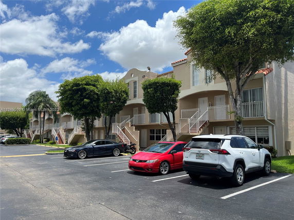 Front view of multi-story townhouses with a parking area in front.