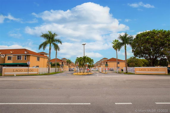 Front view of a residential complex with a gated entrance and palm trees.