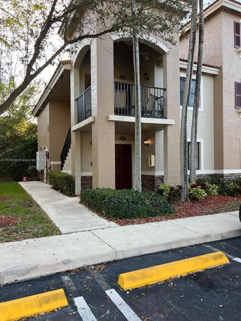 Front view of a two-story building with arched balcony and side staircase.