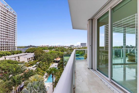 View from a balcony overlooking a pool area and surrounding buildings.
