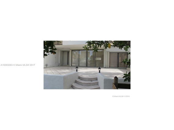 Front view of a house with large sliding glass doors and a tiled patio area.