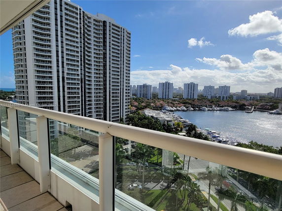 Panoramic view from a high-rise building overlooking other tall residential buildings and a body of water with boats.