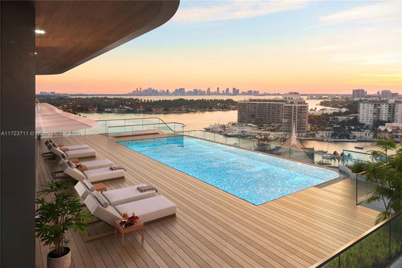 Rooftop swimming pool with lounge chairs offering a panoramic city and water view.