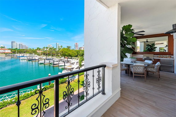 Balcony view overlooking a marina with boats, skyscrapers in the background, and outdoor seating area visible.