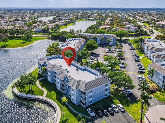 Aerial view of residential buildings near a water body with a parking area.